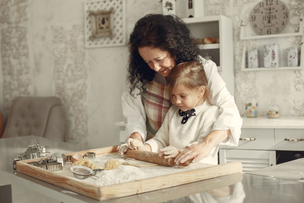 A joyful bonding moment of a mother and daughter baking cookies together at home.